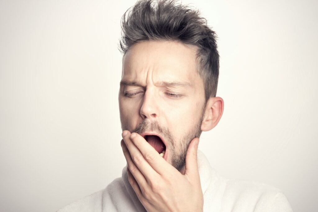 man yawning hand over mouth