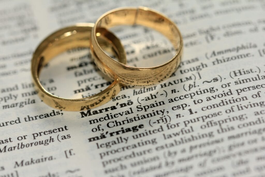 Two mens rings on dictionary over the word marriage