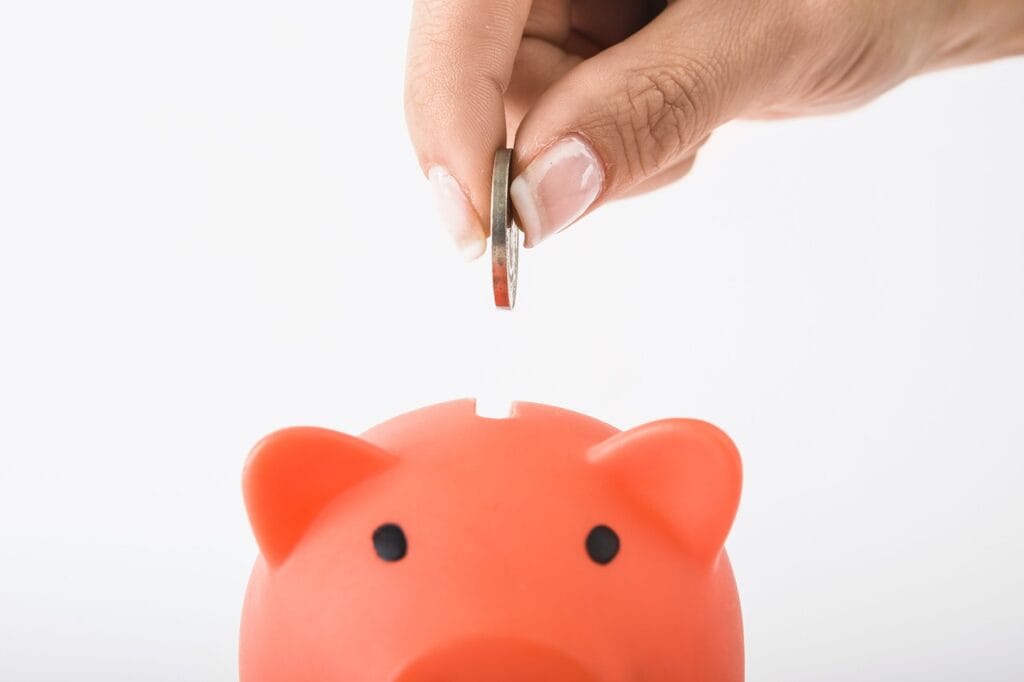 woman's hand putting money in piggy bank