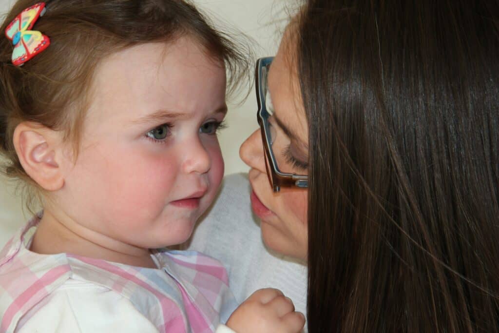 lady holds upset toddler girl