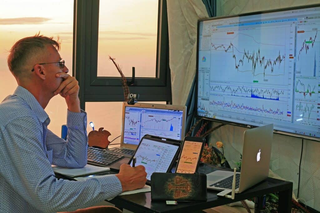 Man sitting in front of screens with financial graphs