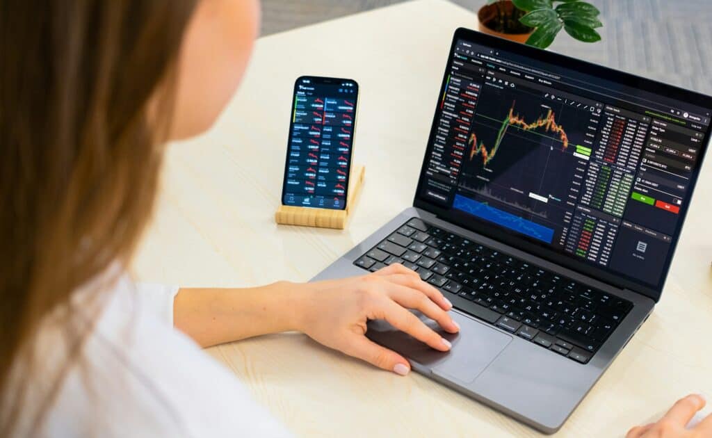 woman looking at stocks on computer and phone