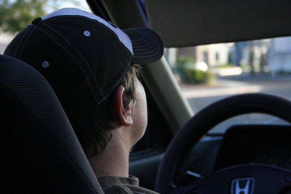 back of boy's head with baseball cap driving car