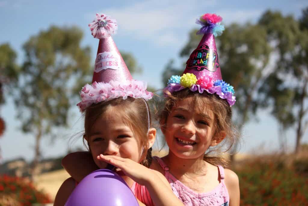 girls with balloon wearing birthday party hats