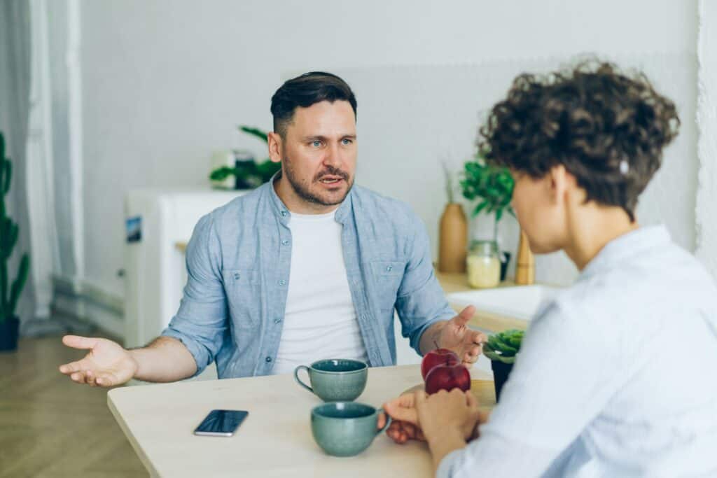 angry man at table talking to woman