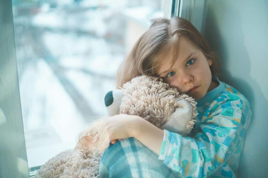 sad preschool girl holding teddy bear