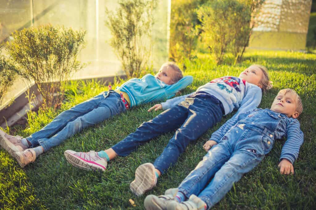 Three kids lying on grass