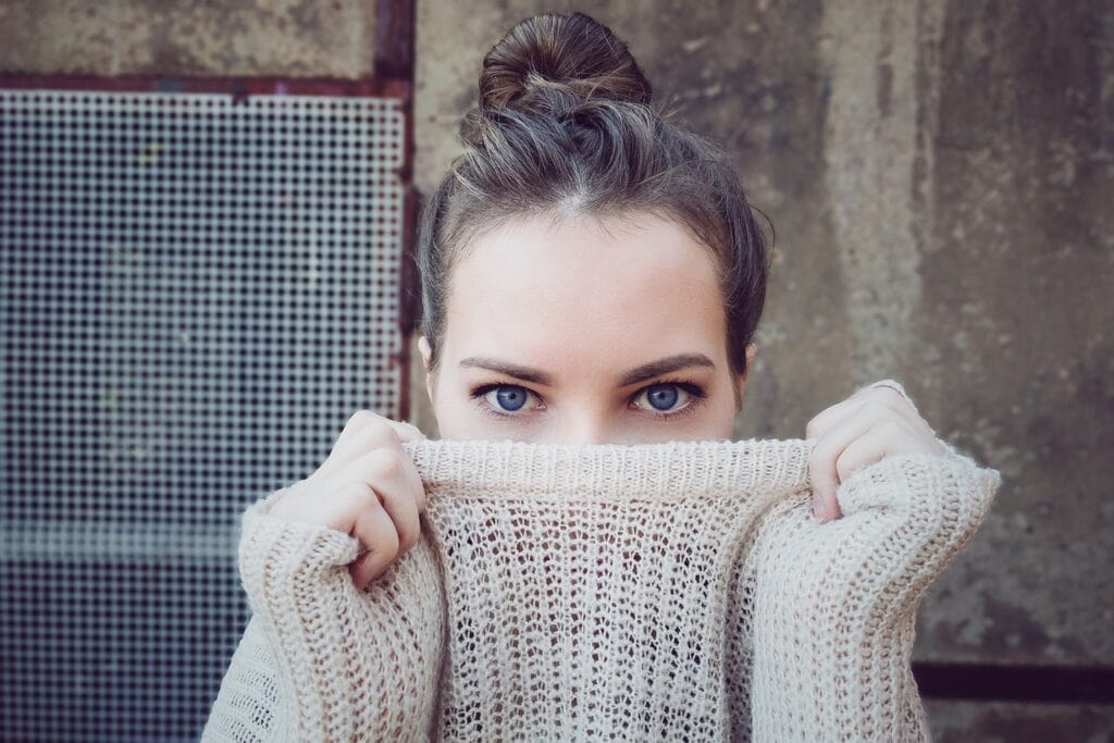 teen holding sweater neck over face