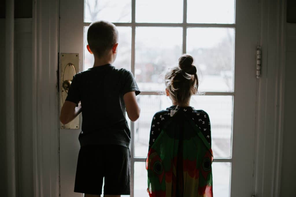 young boy and girl looking out door