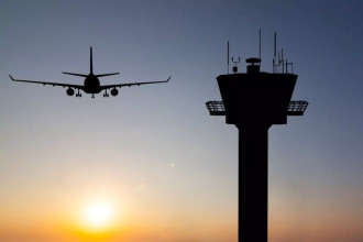 airplane taking off near the control tower with the sunset in the background
