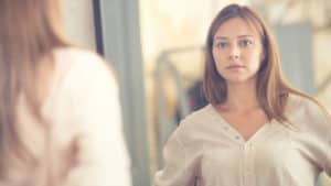 young woman looking in mirror without smile