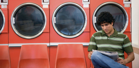Man sitting in a laundromat reading a newspaper