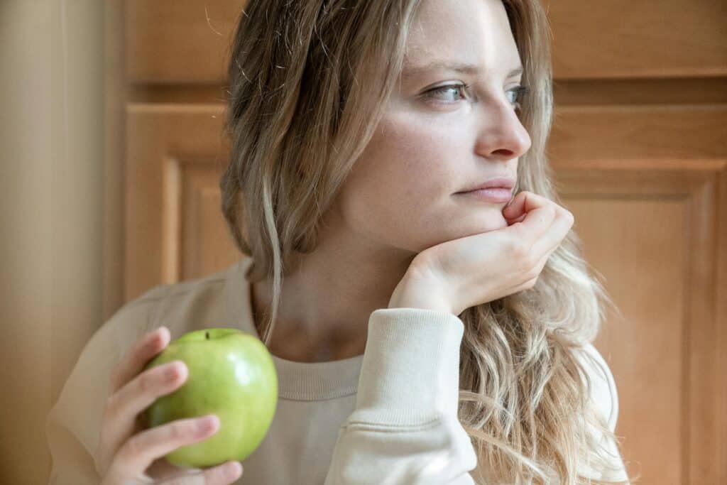 woman holding apple looking into distance