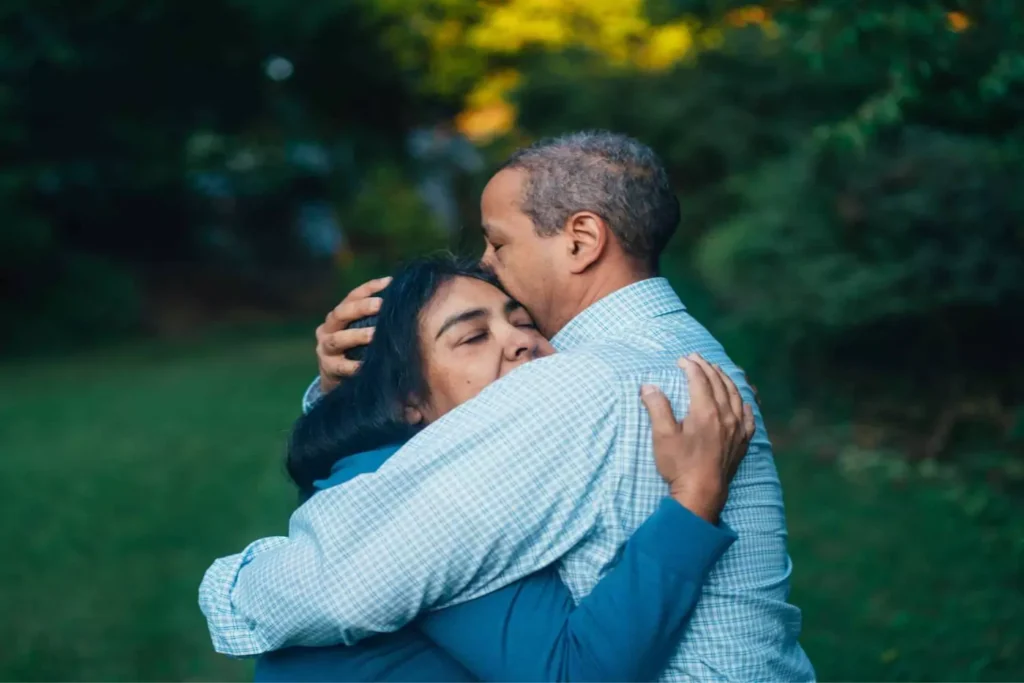 A couple embraces tenderly in a peaceful outdoor setting, reflecting the emotional journey of being diagnosed with cancer and finding strength together.