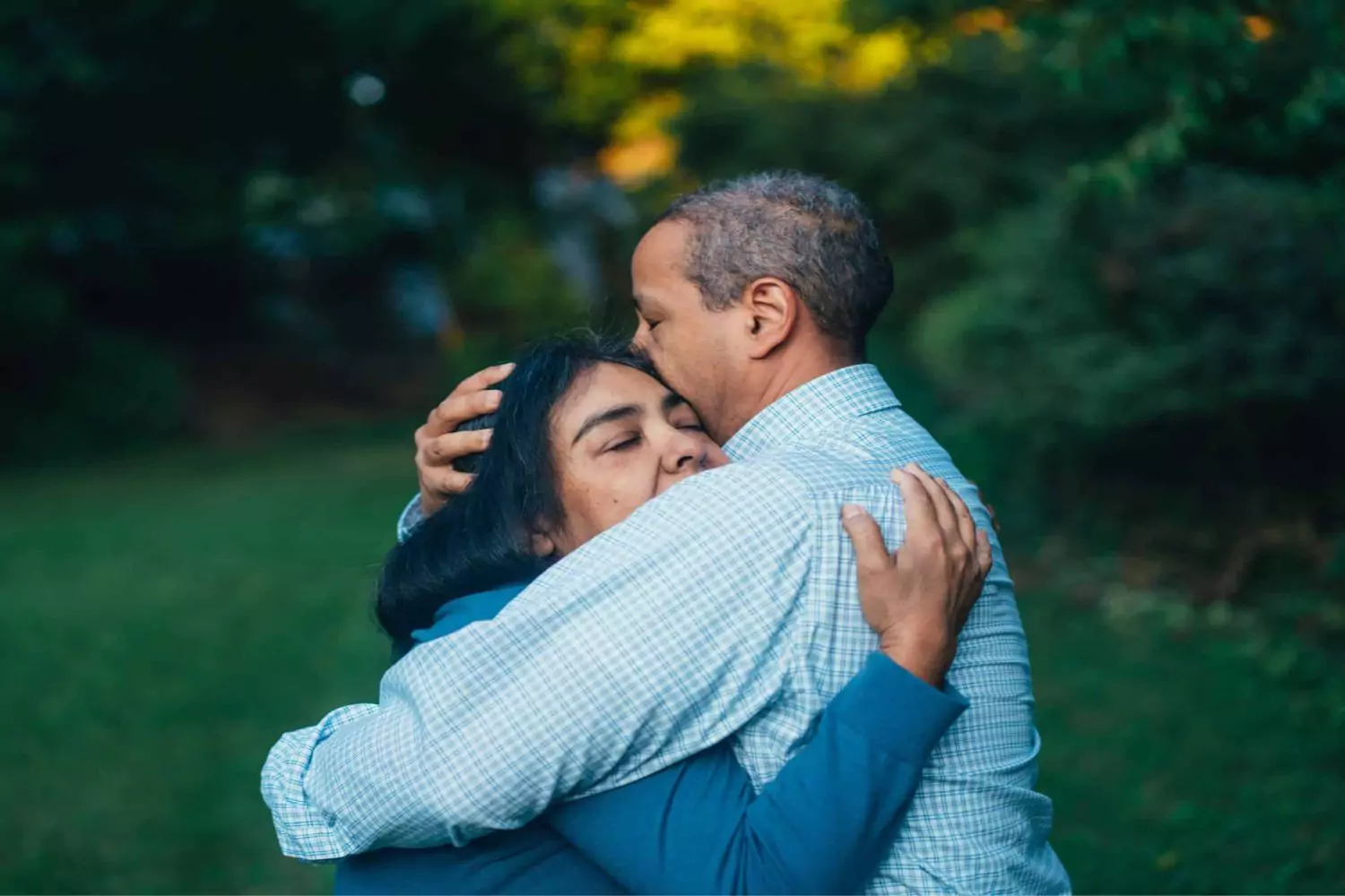 A couple embraces tenderly in a peaceful outdoor setting, reflecting the emotional journey of being diagnosed with cancer and finding strength together.