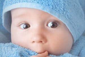 Bright-eyed newborn wrapped in a blue towel