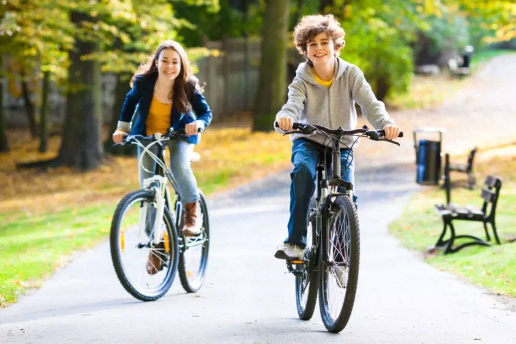 Healthy identity as seen by a smiling boy and girl on their bikes with big smiles on their faces