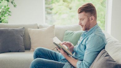 Profile image of man sitting on a couch reading a book
