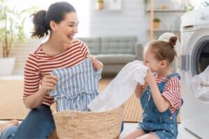 child doing laundry with her mother