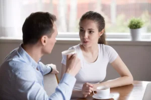 Communicating your expectations in marriage is important. A young couple sits at a table talking about their expectations in their marriage.