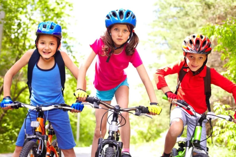 Three little girls riding bikes with helmets on