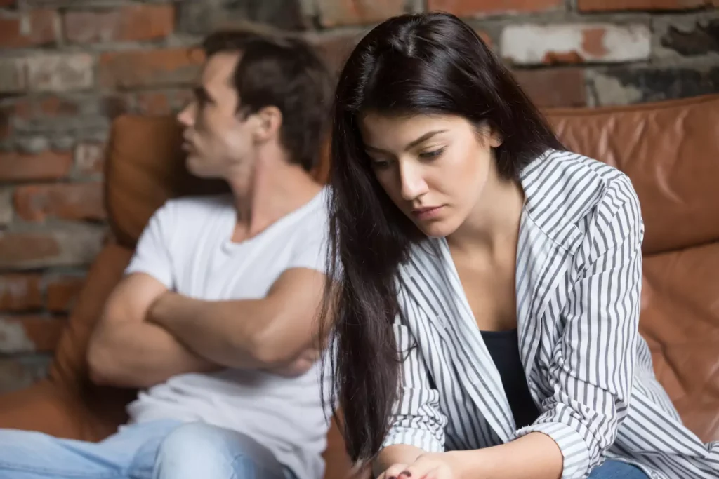 A couple sits on a couch in verbal conflict. they can build a healthy marriage with authentic communication.
