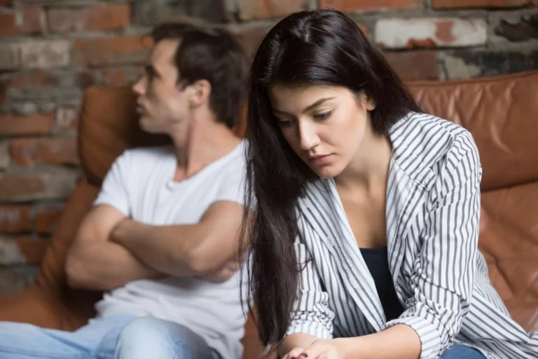 A couple sits on a couch in verbal conflict. they can build a healthy marriage with authentic communication.