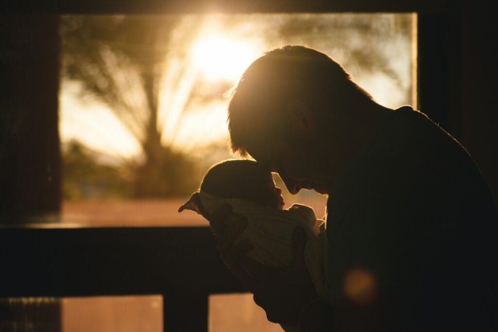 dad leaning head against baby sunset