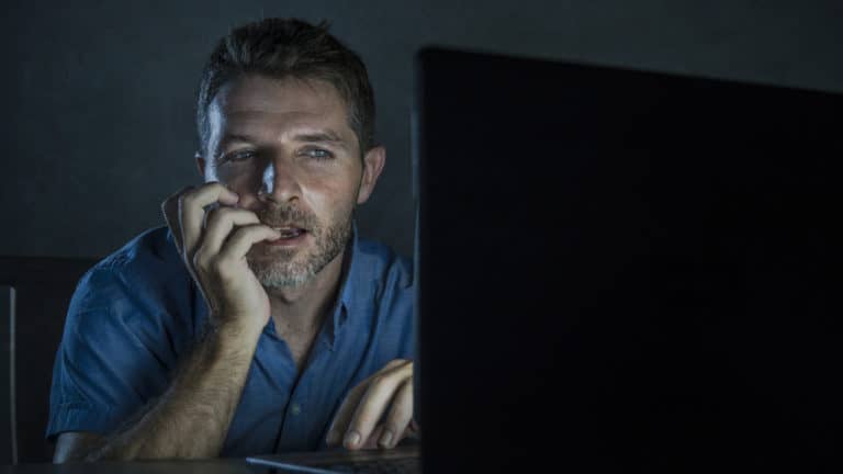 man nervously looking at computer screen