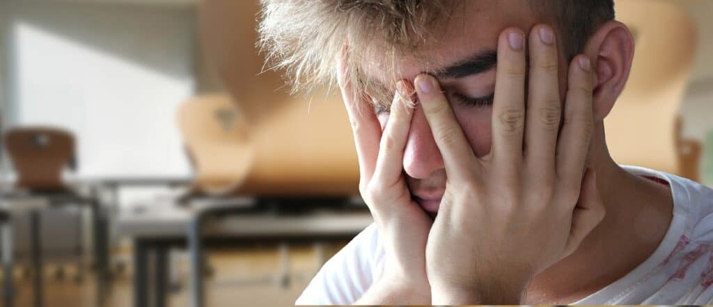 young man holding hands over face