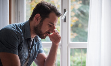 Worried man looking thoughtful out of window