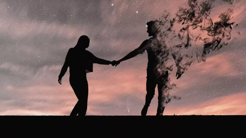Silhouette of a couple holding hands at sunset, but the man is fading away because of the alienation, anger, and anxiety in their marriage.