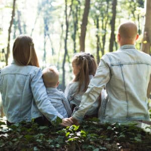 Shown from behind, a couple sitting with their two young kids outside; all are wearing denim jackets