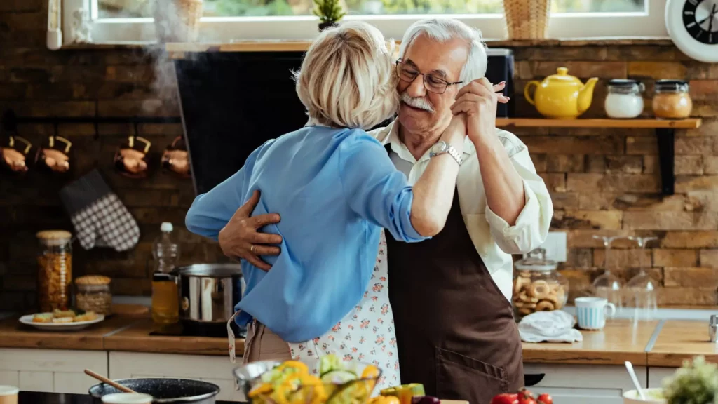 photo of man dancing in the kitchen with his wife. They actively invest in fun in their marriage and protect themselves against boring routines.