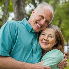 Senior couple hugging, looking at camera