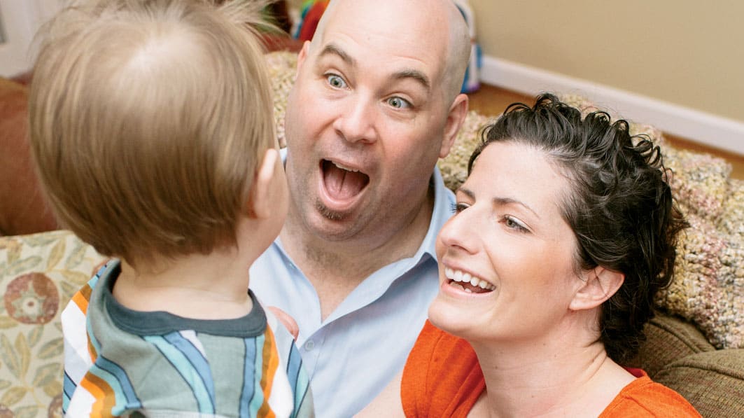 Husband and wife making happy faces to their son