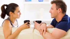 Young couple sitting on a sofa, drinking coffee, talking