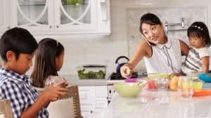 Busy mother organizing children at breakfast in kitchen