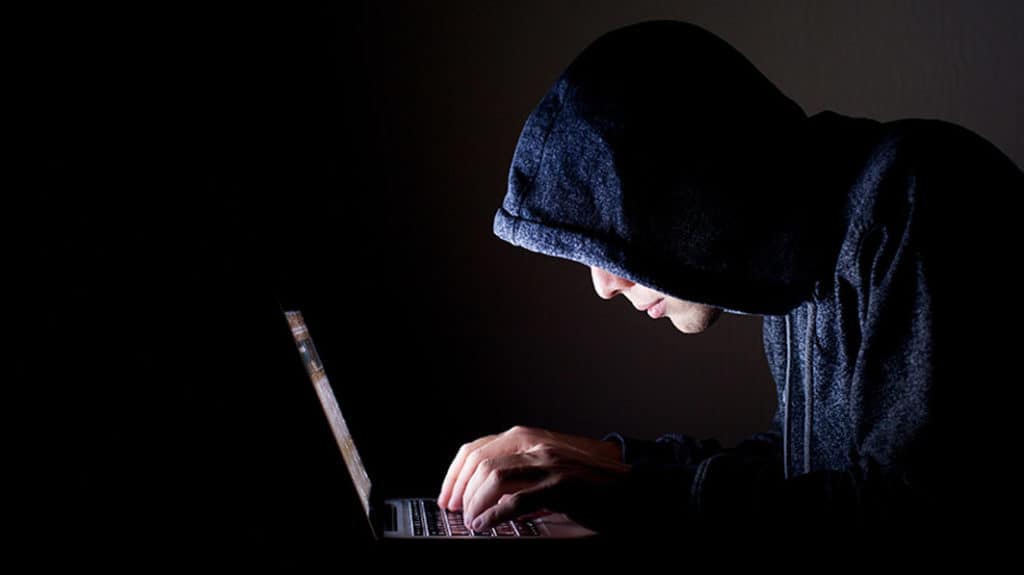 Sneaky man looking at a computer in the dark, struggling to deal with a pornography addition