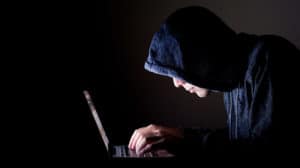 Sneaky man looking at a computer in the dark, struggling to deal with a pornography addition