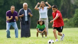 Family looks on as boy plays a soccer game