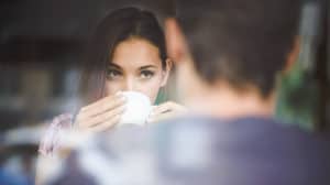 A young couple looks at each other across a table while having coffee in a cafe