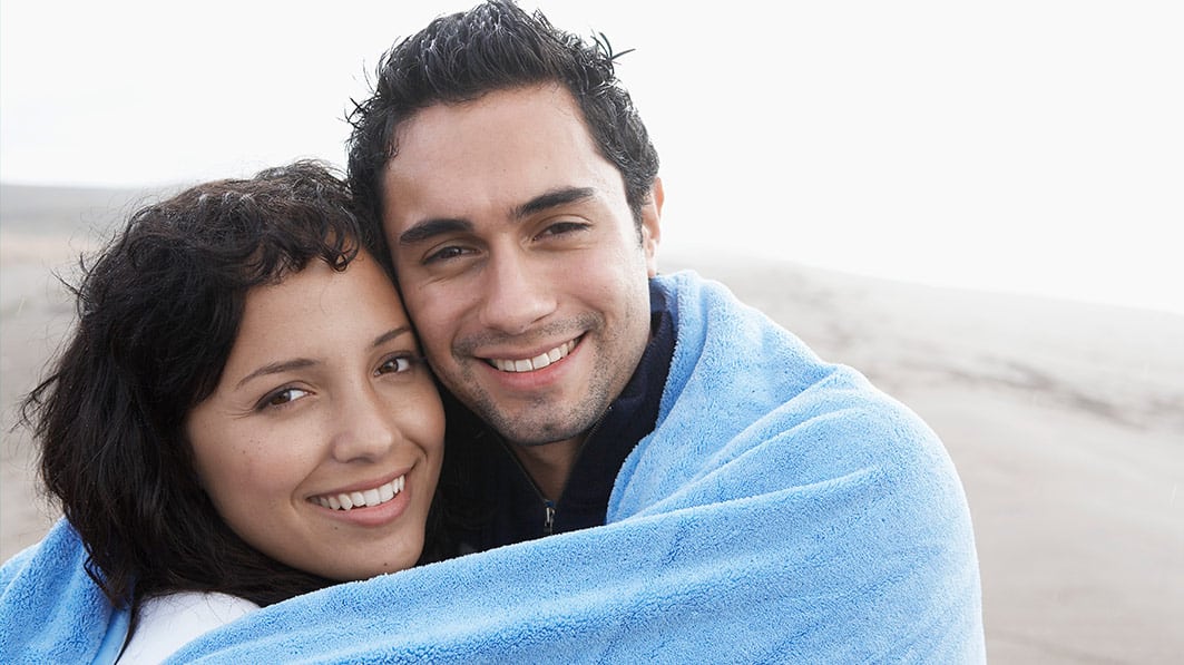 Smiley couple wrapped in a blanket, showing love and respect for one another