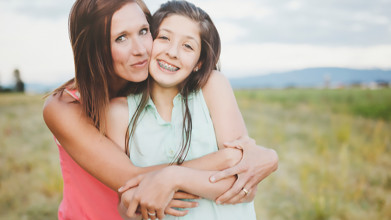 Mother holder her daughter in her arms with a flowered field in the background