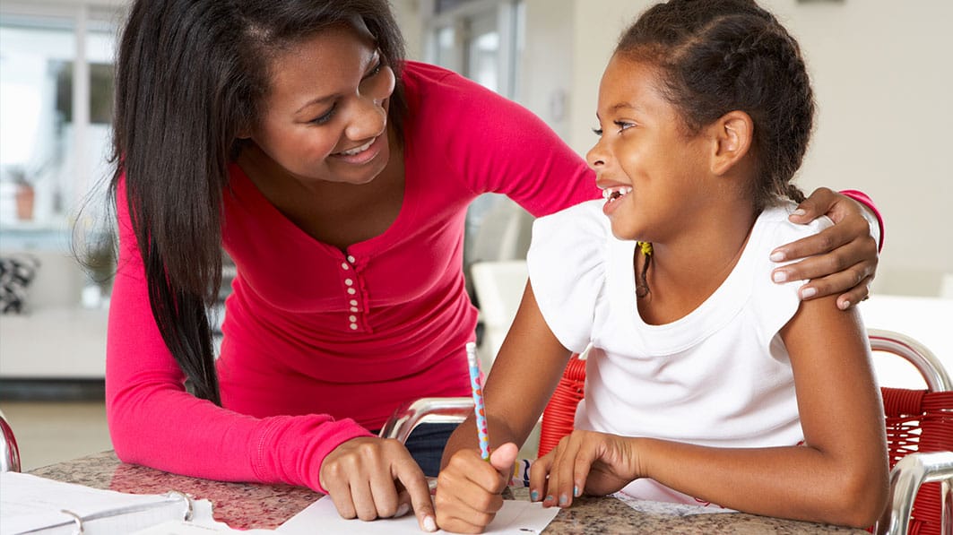 Mother with her arm around her daughter, helping her with her homework