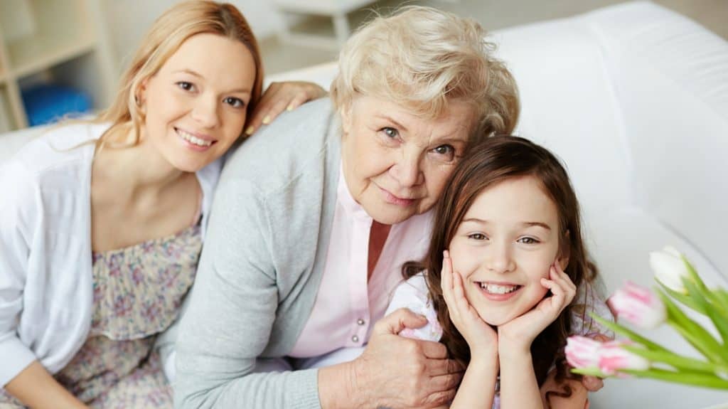 Grandmother smiling beside her two granddaughters.
