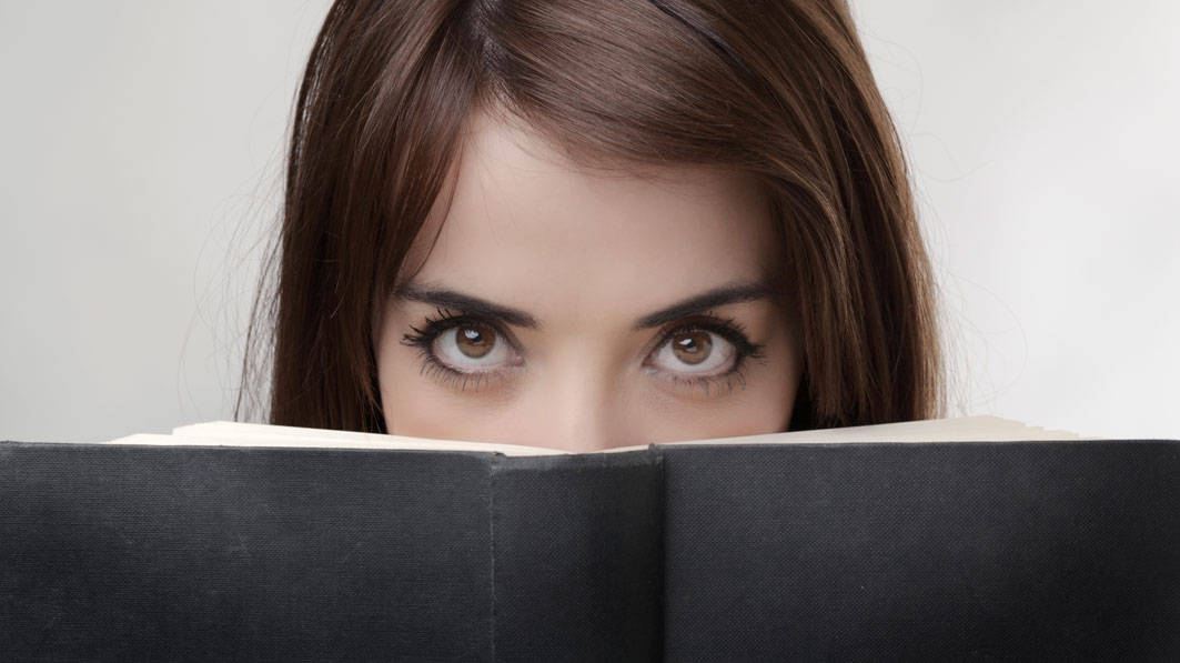 Woman looking intensely over a black covered book.
