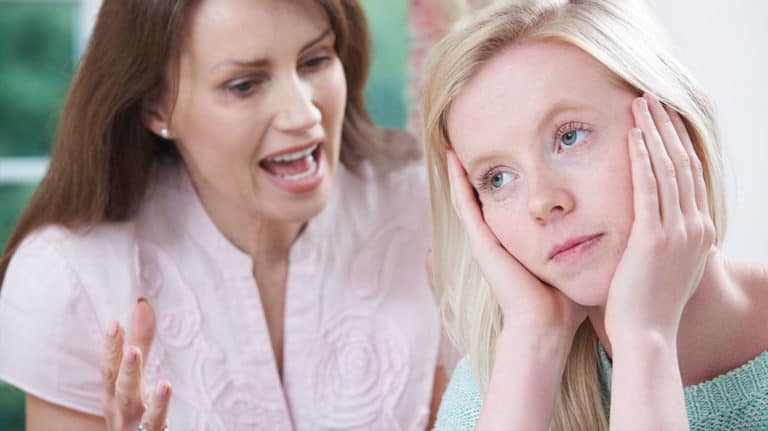Upset mom talking at her teen daughter who doesn’t care and is turned away and staring off into space