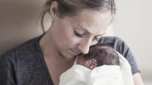 Young mother tenderly holding her premature newborn baby, pearl Huene.