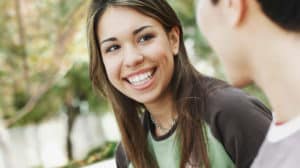 Teen girl smiling at a boy standing beside her